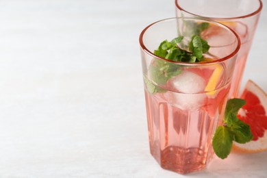 Photo of Delicious cocktails with grapefruit, mint and ice balls on white table, space for text