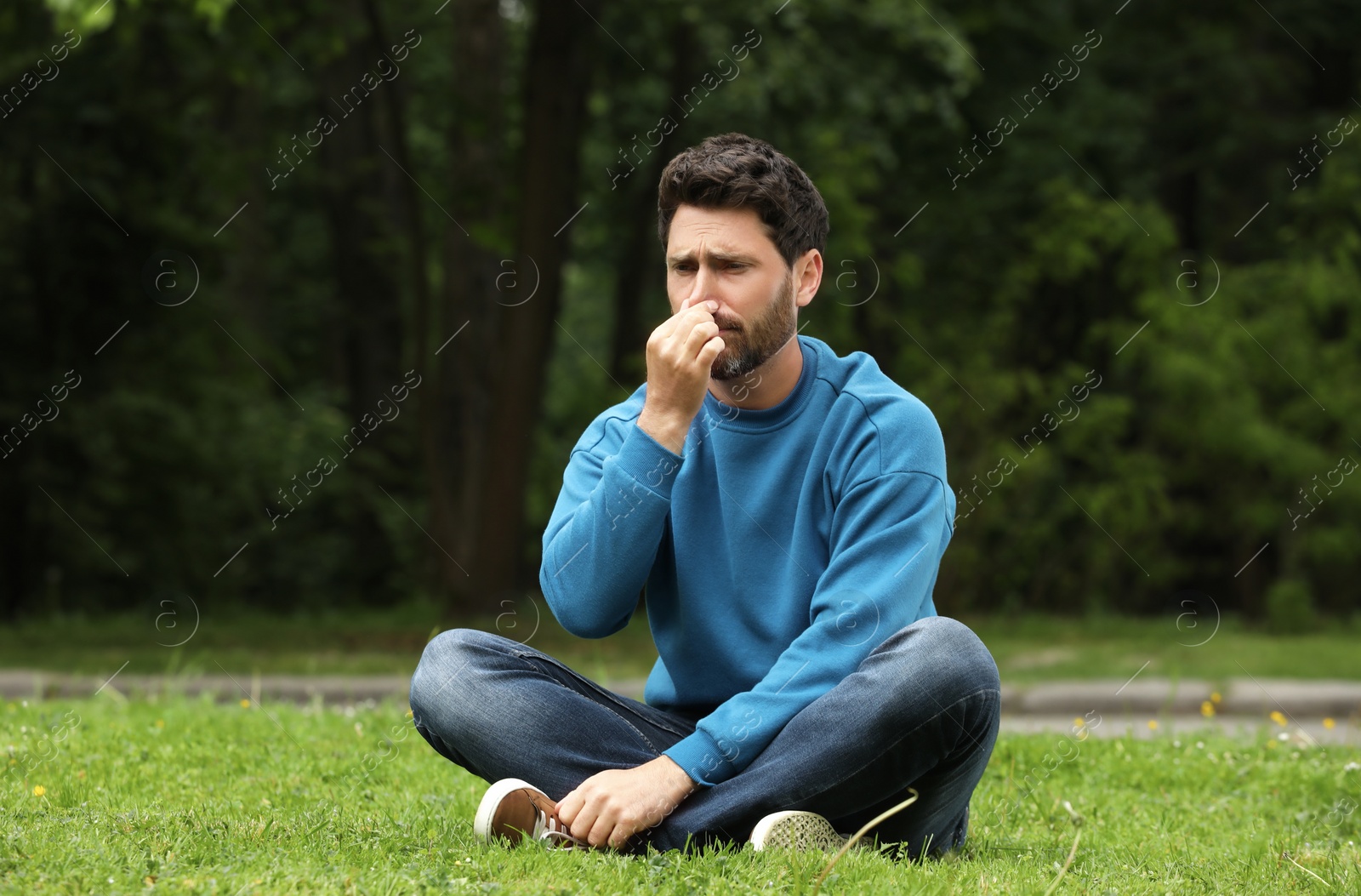 Photo of Man suffering from seasonal spring allergy on green grass in park