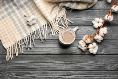 Flat lay composition with coffee and warm plaid on black wooden table, space for text