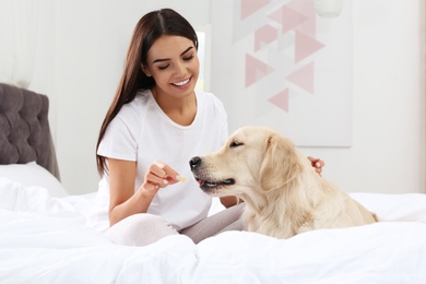 Young woman and her Golden Retriever dog on bed at home