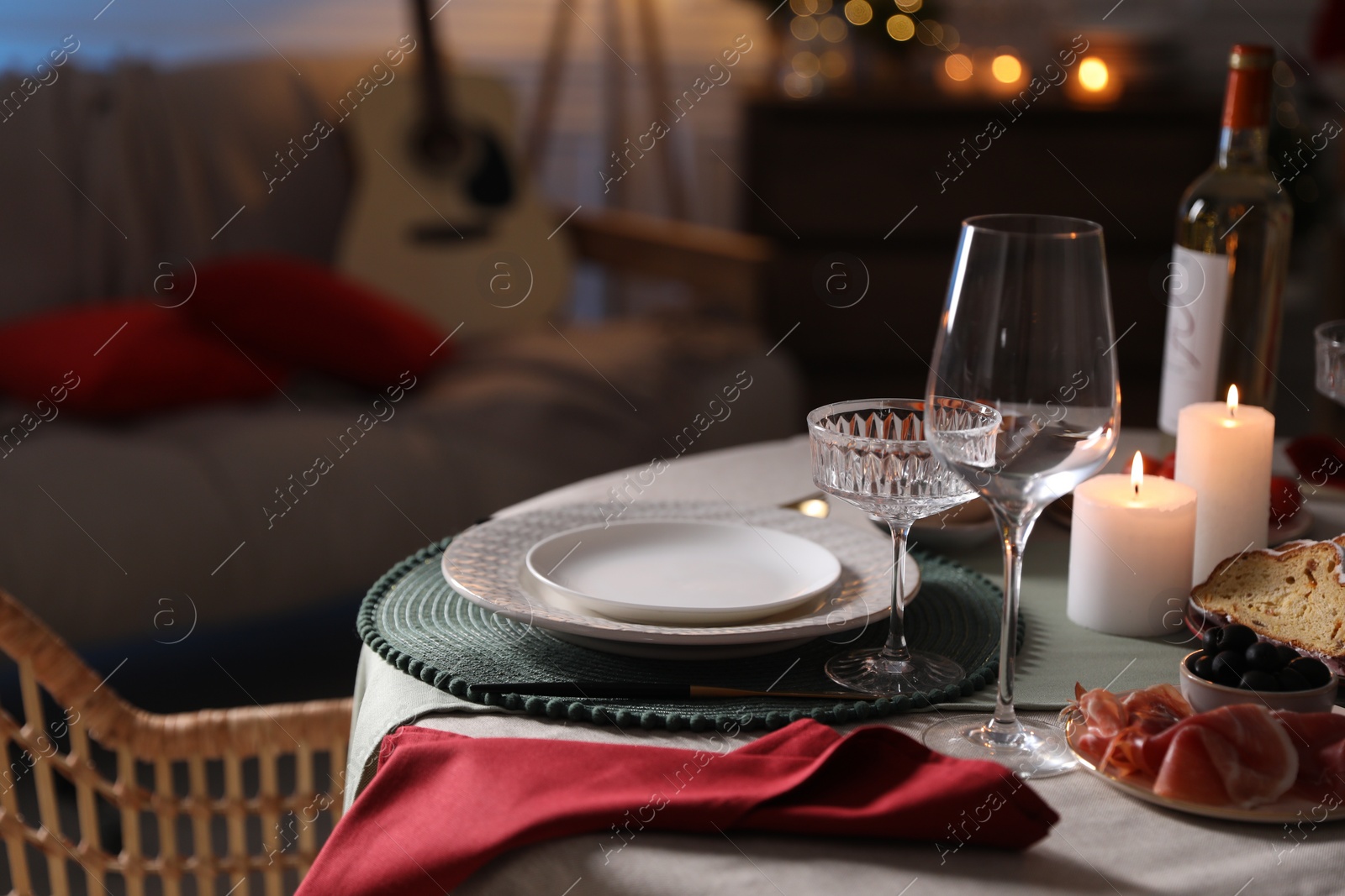 Photo of Table setting with burning candles, appetizers and dishware indoors, space for text. Christmas celebration