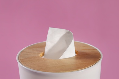 Photo of Holder with paper tissues on pink background, closeup