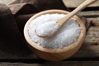 Photo of Organic salt in bowl and spoon on wooden table, closeup