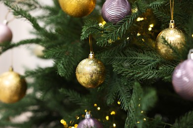 Photo of Beautiful Christmas balls hanging on fir tree, closeup