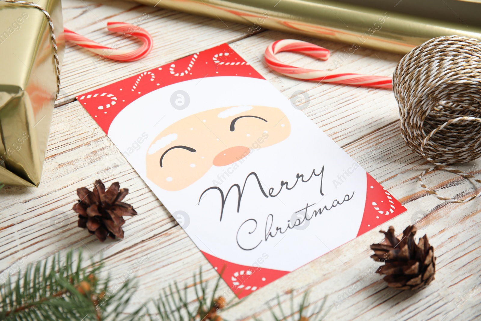 Photo of Christmas card and pine cones on white wooden background, closeup