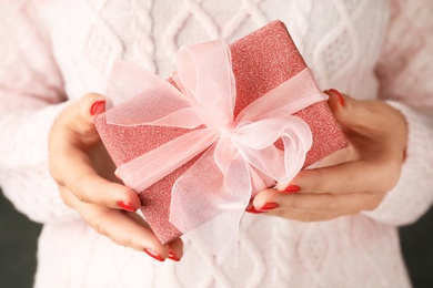 Woman holding beautiful Christmas gift with bow, closeup