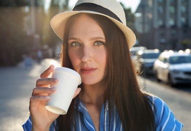 Photo of Beautiful young woman with nose piercing drinking coffee outdoors