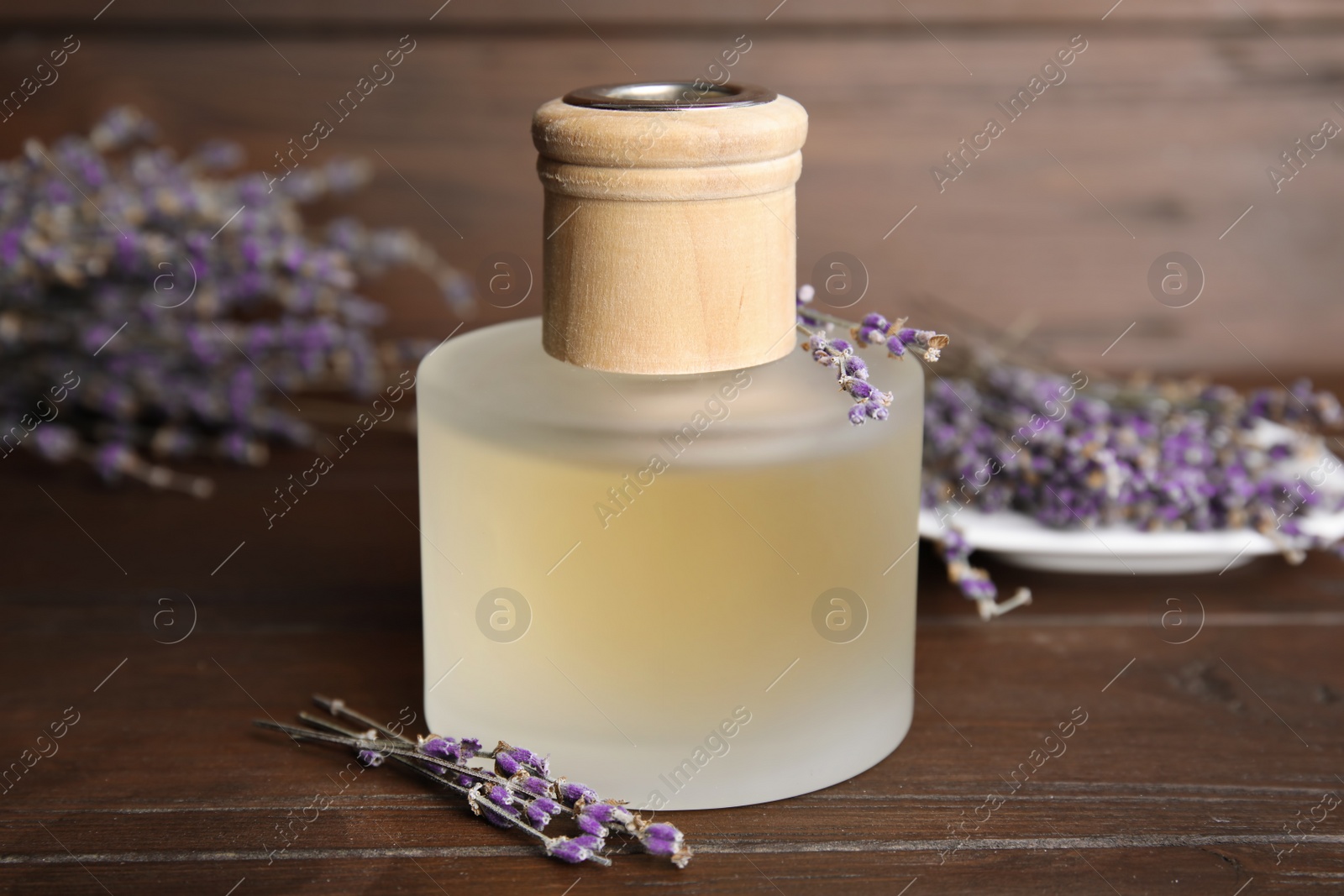 Photo of Bottle with aromatic lavender oil on wooden table