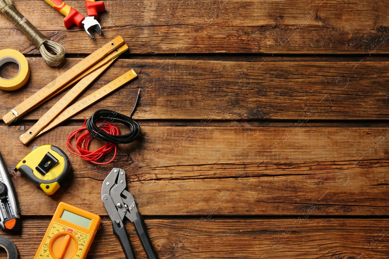 Photo of Wires and electrician's tools on wooden table, flat lay. Space for text