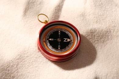 Photo of One compass on beach sand, closeup. Navigation equipment