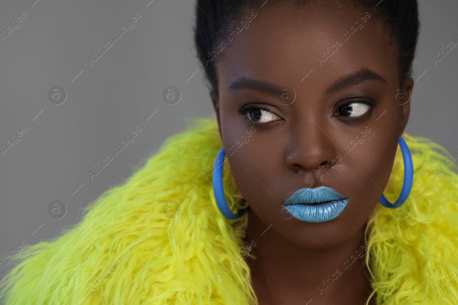 Photo of Fashionable portrait of beautiful woman with bright makeup on grey background, closeup. Space for text