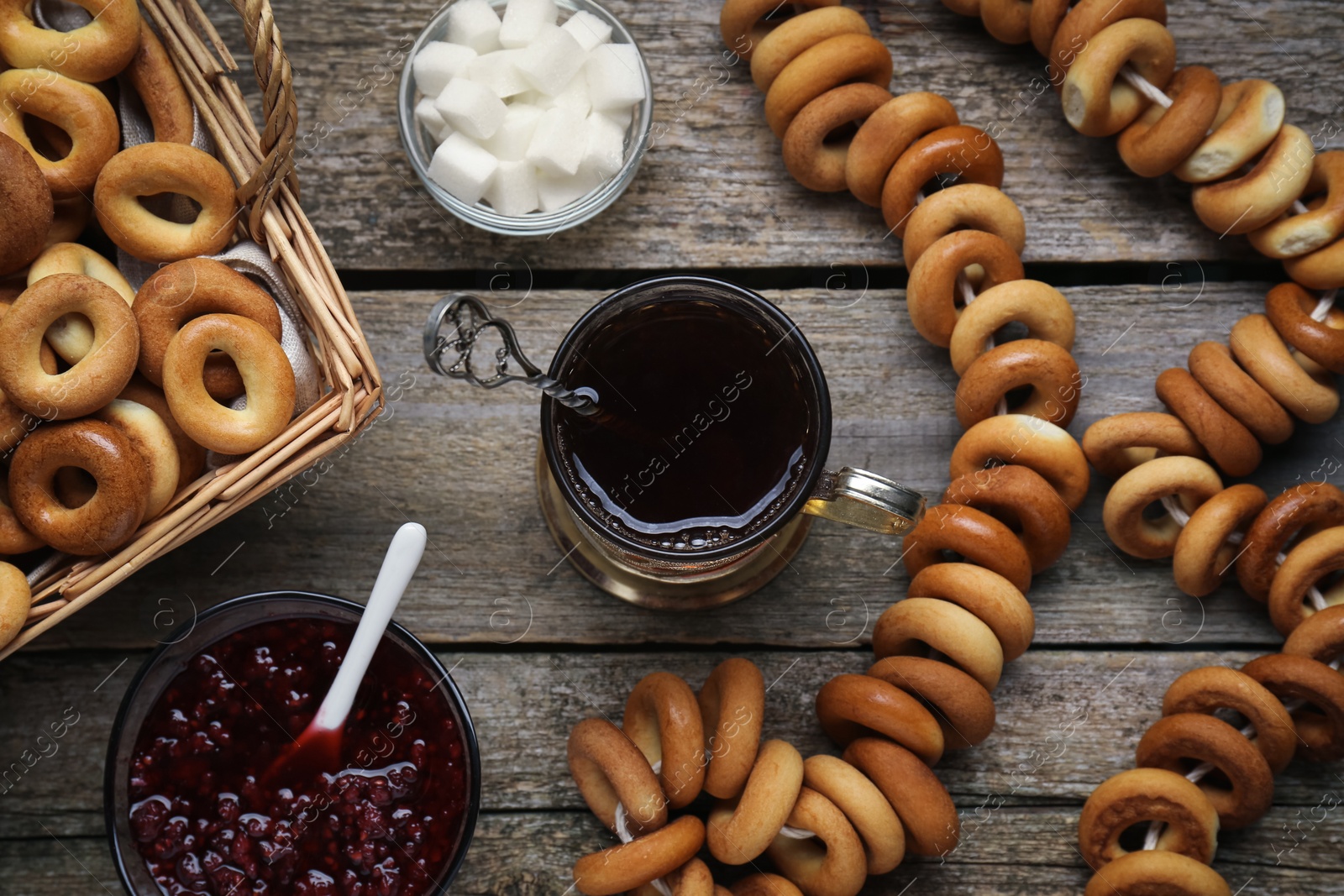 Photo of Flat lay composition with delicious ring shaped Sushki (dry bagels) and cup of tea on wooden table