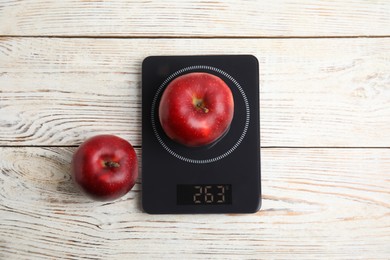 Photo of Ripe red apples and electronic scales on white wooden table, flat lay