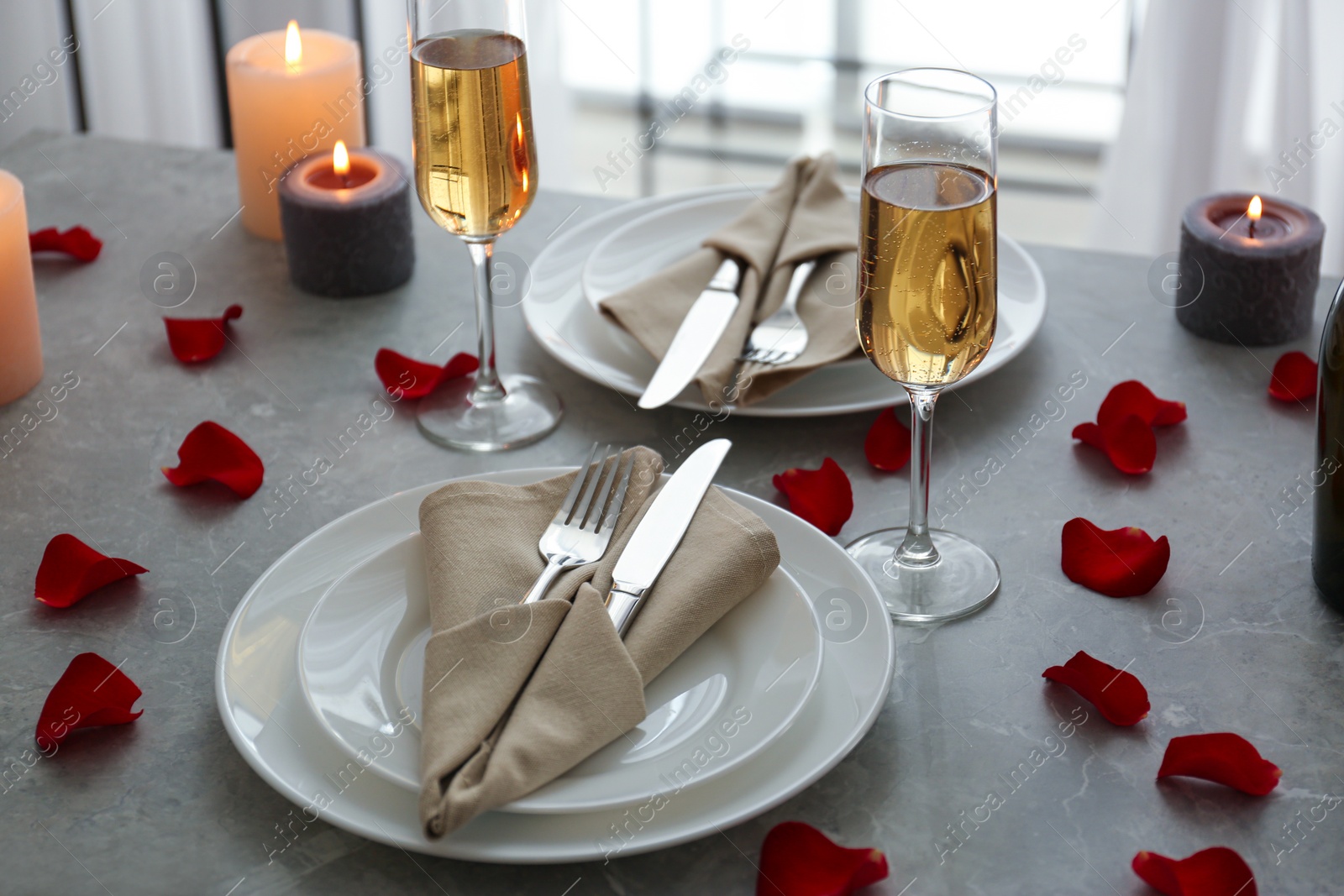 Photo of Romantic table setting with burning candles and rose petals indoors