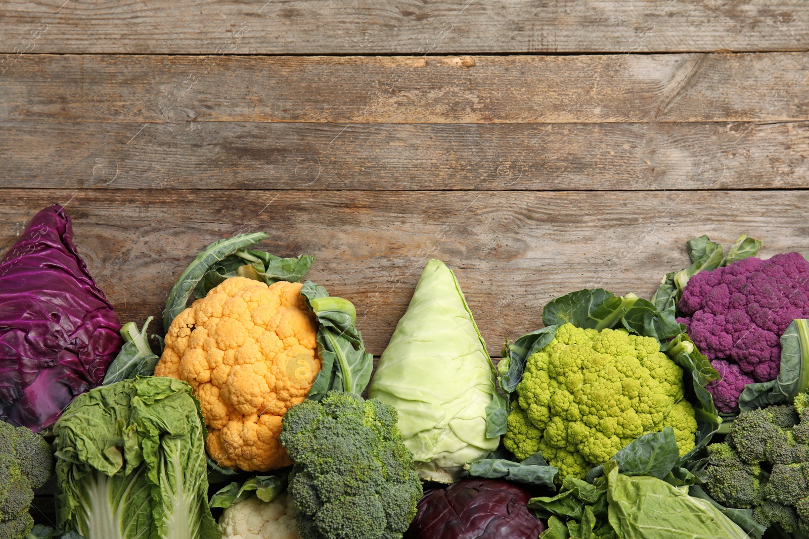 Photo of Different cabbages on wooden table, top view. Healthy food