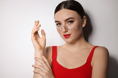 Photo of Beautiful woman with glitter freckles on light background