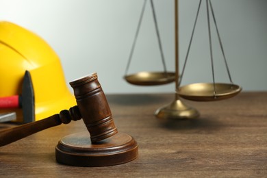 Construction and land law concepts. Gavel, scales of justice, hard hat and hammer on wooden table, closeup