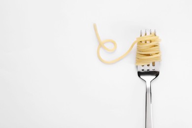 Photo of Fork with tasty pasta on white background, top view. Space for text