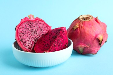 Photo of Delicious cut and whole red pitahaya fruits on light blue background
