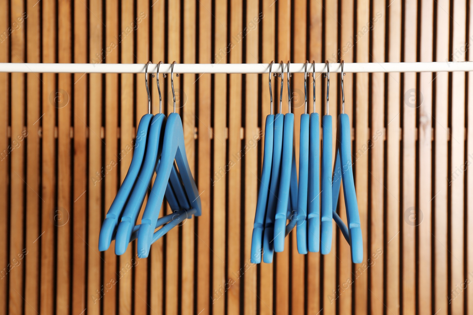 Photo of Empty hangers on rail against wooden background