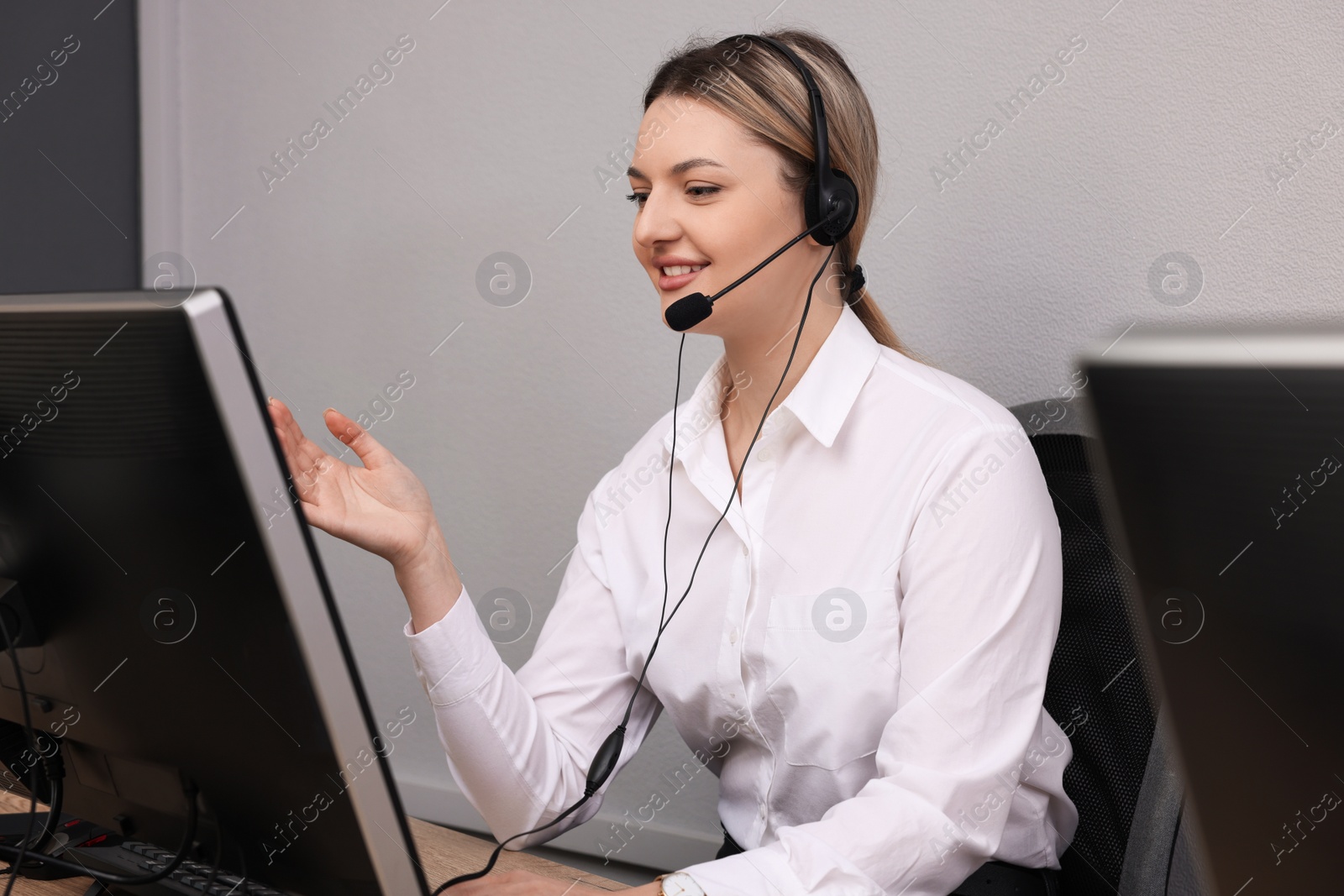 Photo of Young call center operator with headset working in modern office