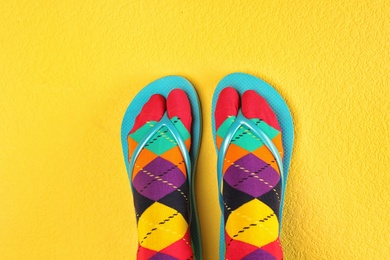 Photo of Woman wearing bright socks with flip-flops on color background