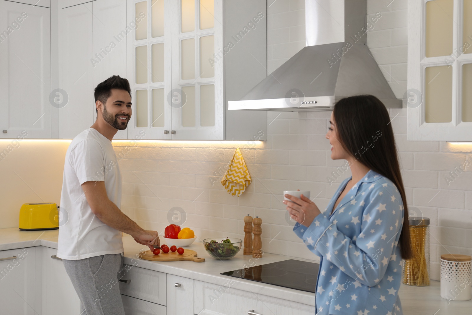 Photo of Happy couple in pajamas cooking and having breakfast at home