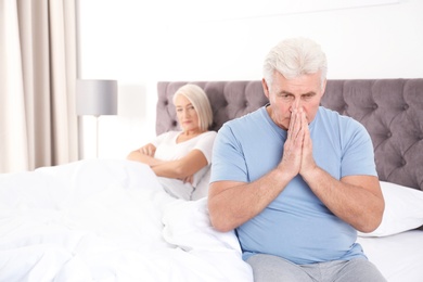 Photo of Mature couple with relationship problems ignoring each other in bedroom