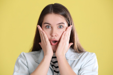 Photo of Portrait of surprised young woman on yellow background