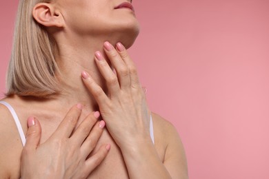 Photo of Woman touching her neck on pink background, closeup