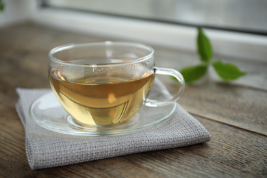 Tasty hot green tea in cup on wooden table, closeup