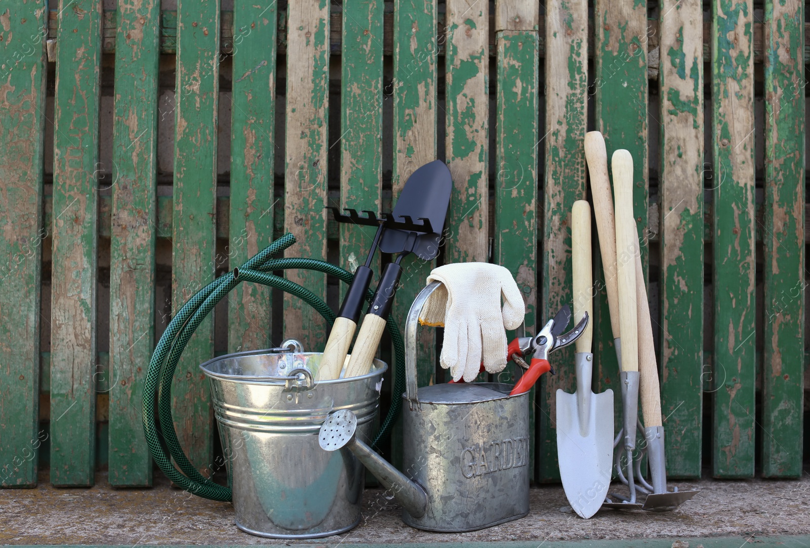 Photo of Set of gardening tools near wooden fence