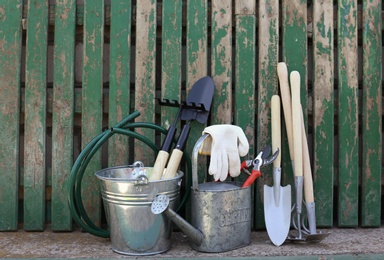 Set of gardening tools near wooden fence