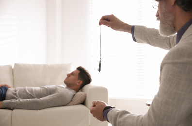 Psychotherapist using pendulum during hypnotherapy   session in office