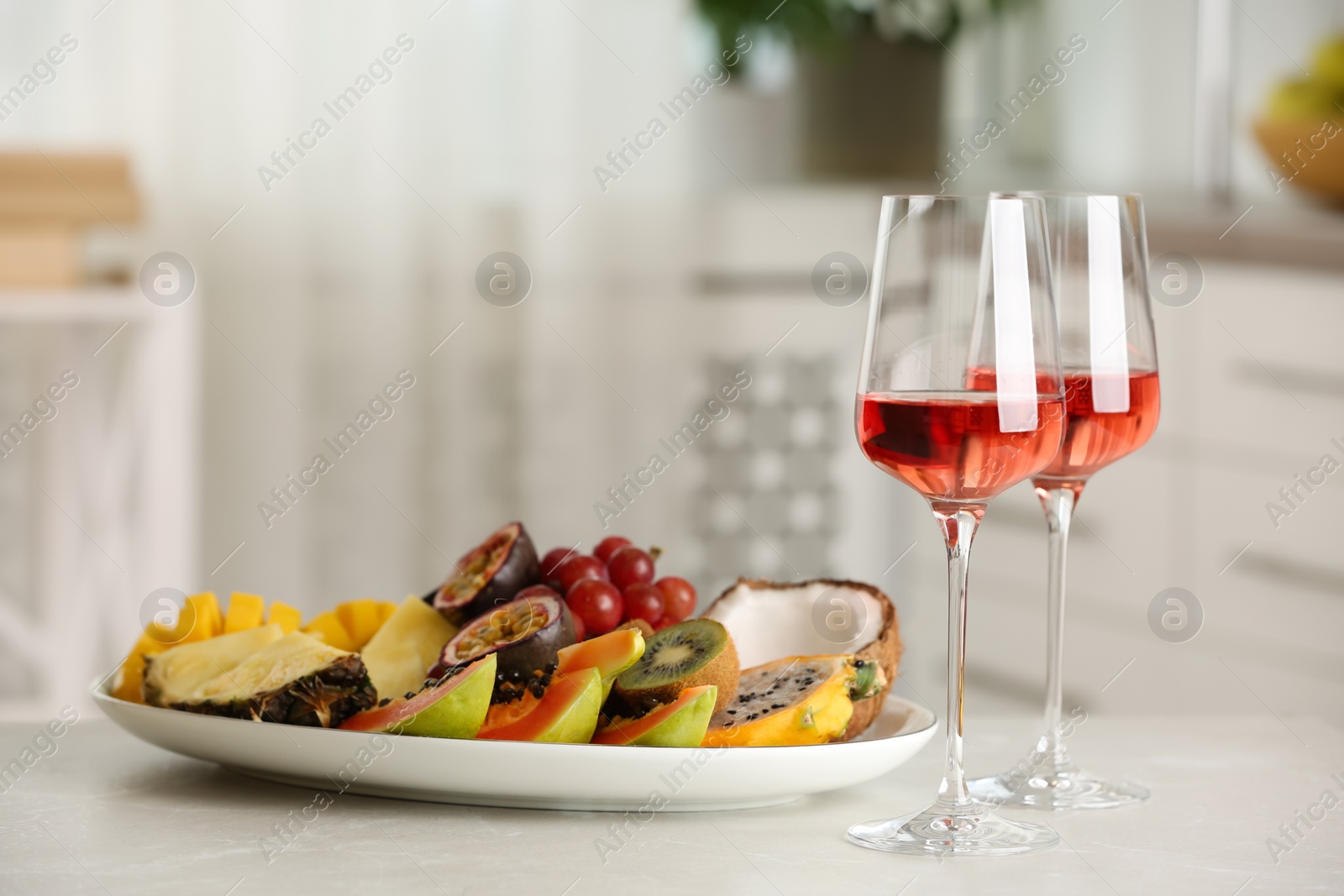 Photo of Delicious exotic fruits and glasses of wine on white table indoors