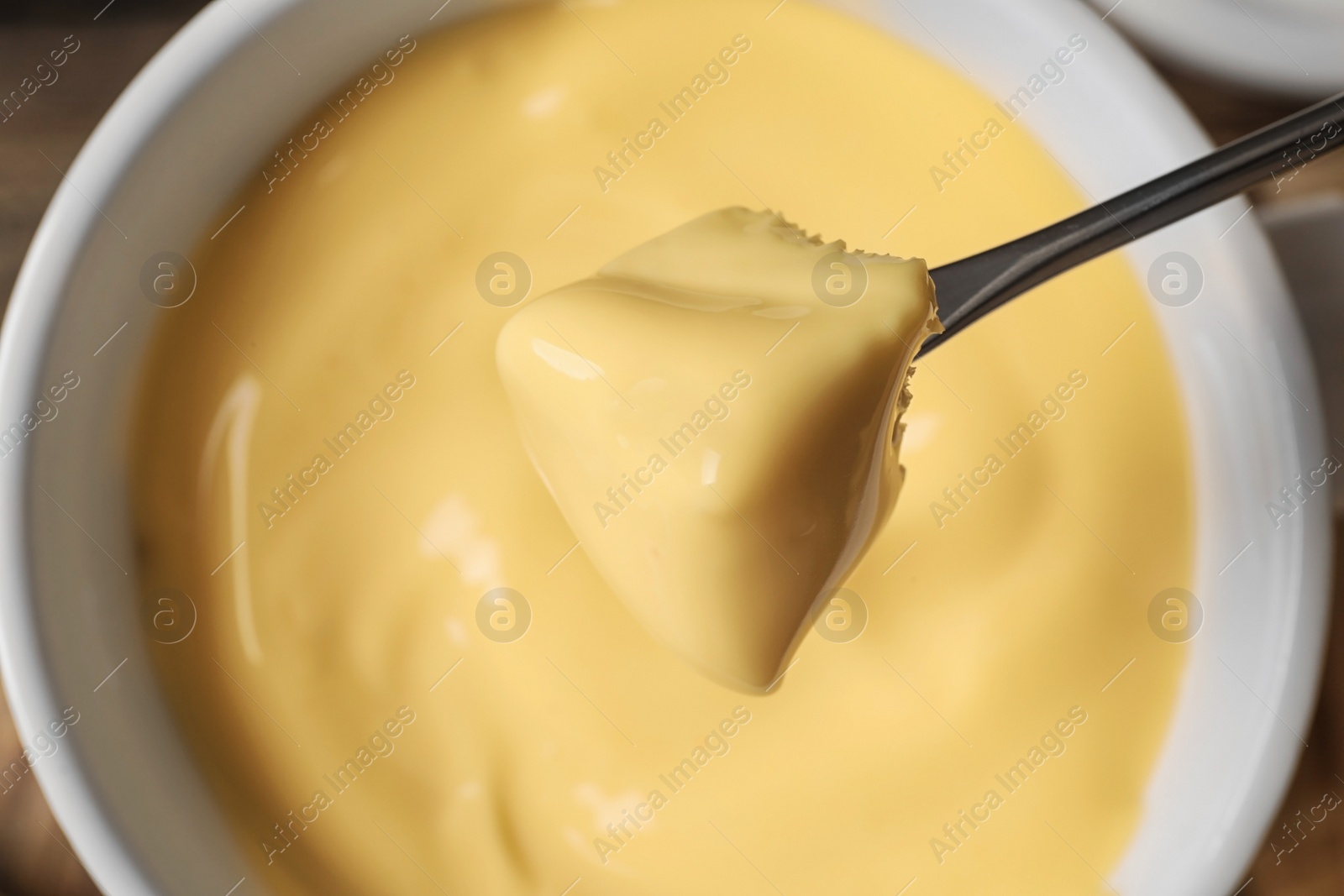 Photo of Dipping bread into tasty cheese fondue, top view