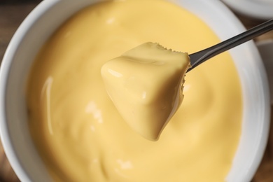 Photo of Dipping bread into tasty cheese fondue, top view