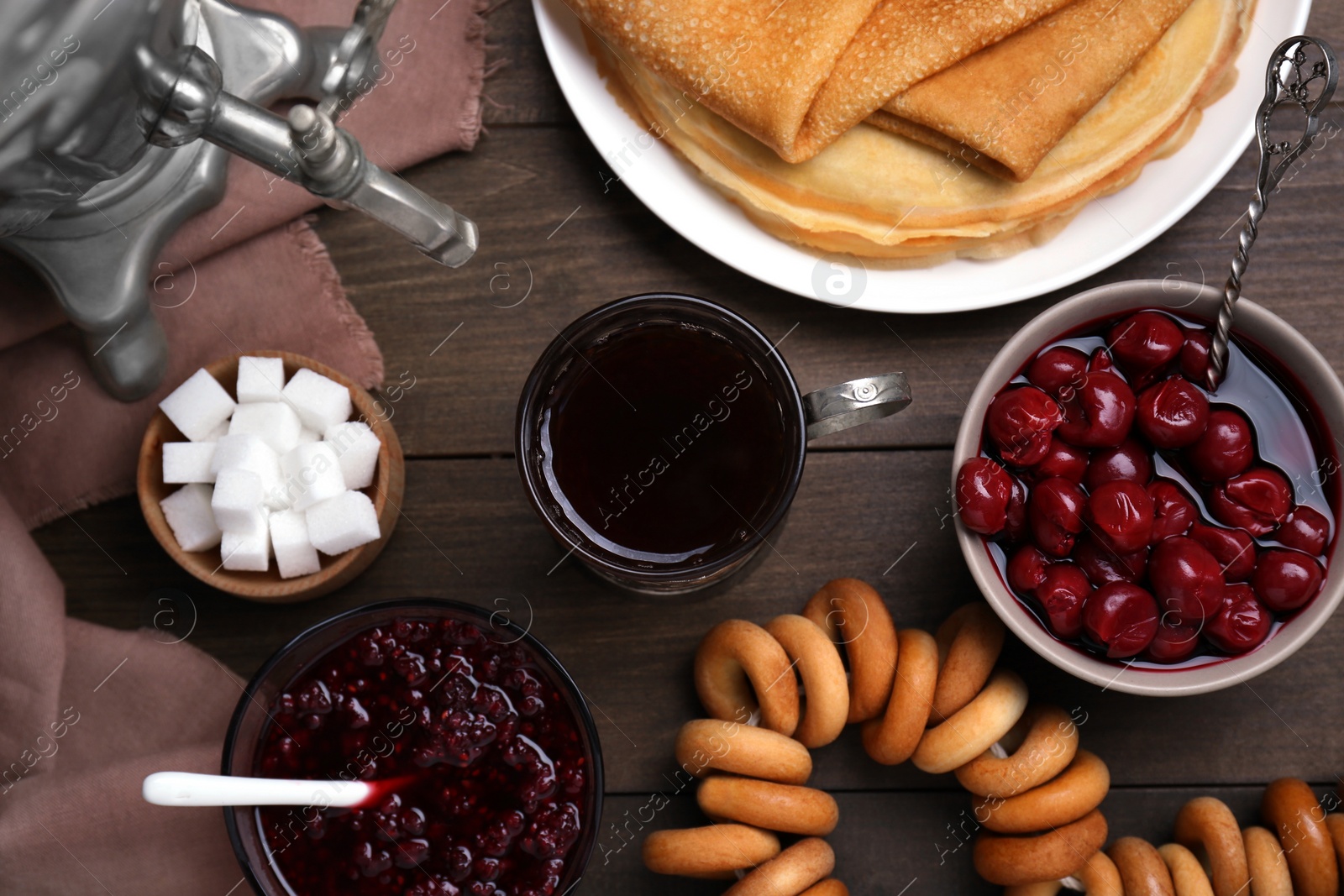 Photo of Metal samovar with cup of tea and treats on wooden table, flat lay