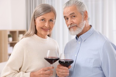 Photo of Affectionate senior couple with glasses of wine indoors