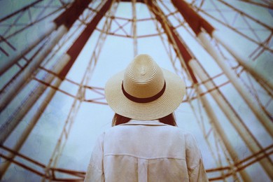 Image of Young woman near Ferris wheel outdoors, back view