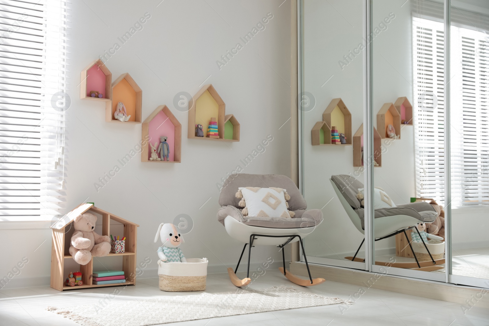 Photo of Cute children's room with house shaped shelves and rocking chair. Interior design
