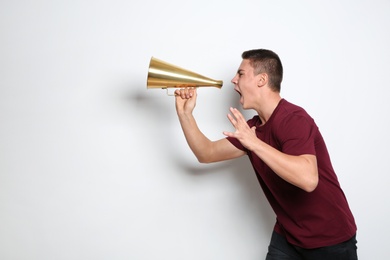 Emotional teenage boy with megaphone on white background. Space for text