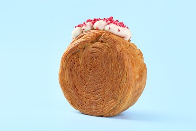 Photo of One supreme croissant with cream on light blue background, closeup. Tasty puff pastry