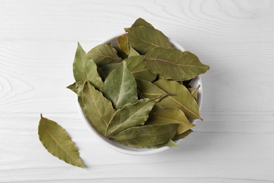 Photo of Bay leaves in bowl on white wooden table, top view