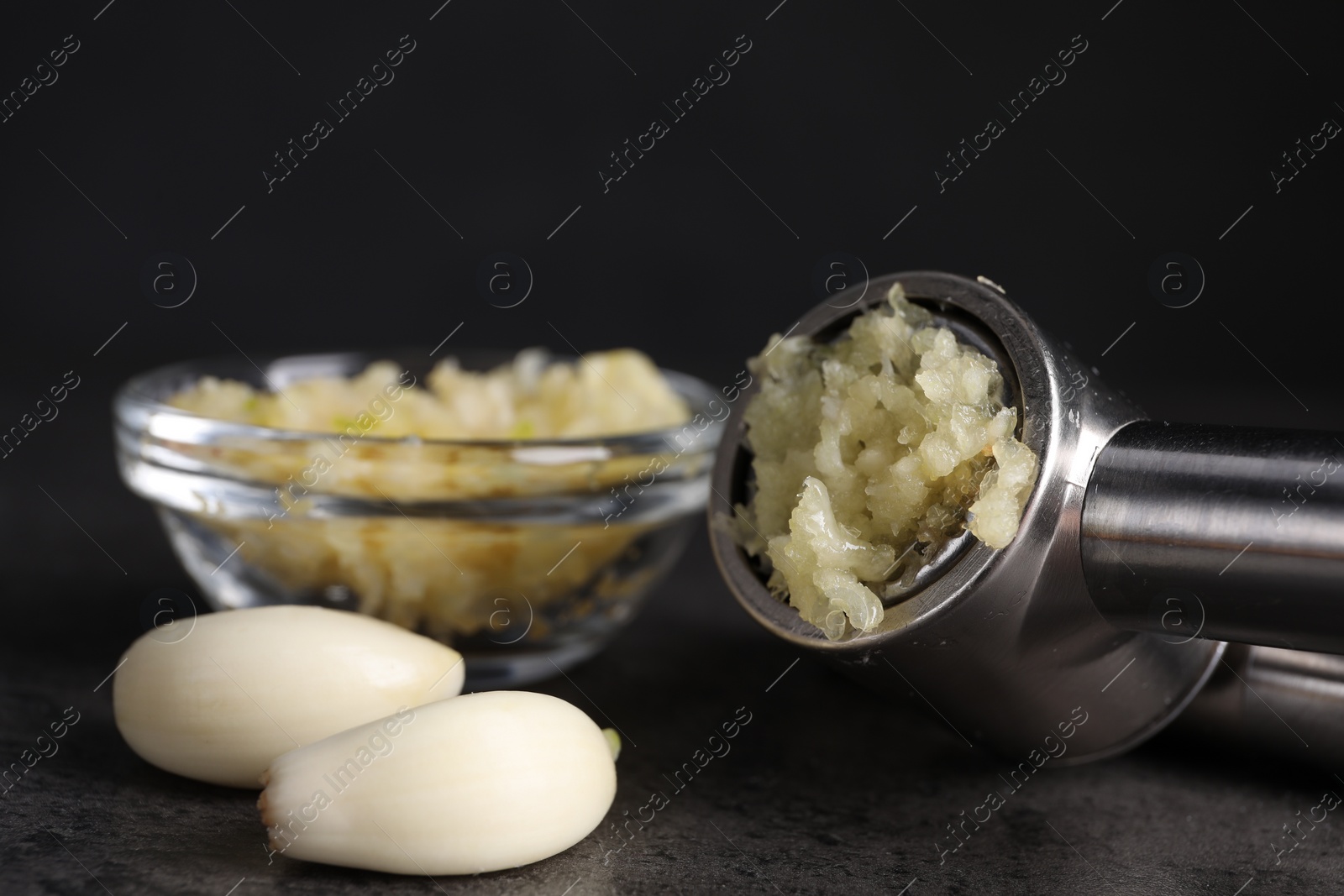 Photo of Garlic press, cloves and mince on grey table, closeup