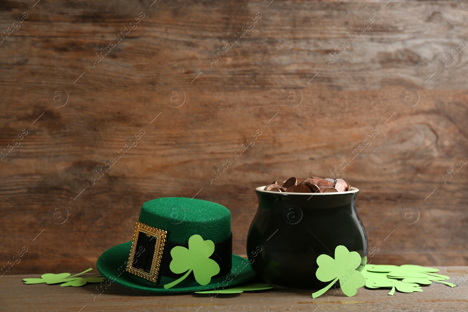 Photo of Pot of gold coins, hat and clover leaves on wooden table, space for text. St. Patrick's Day celebration