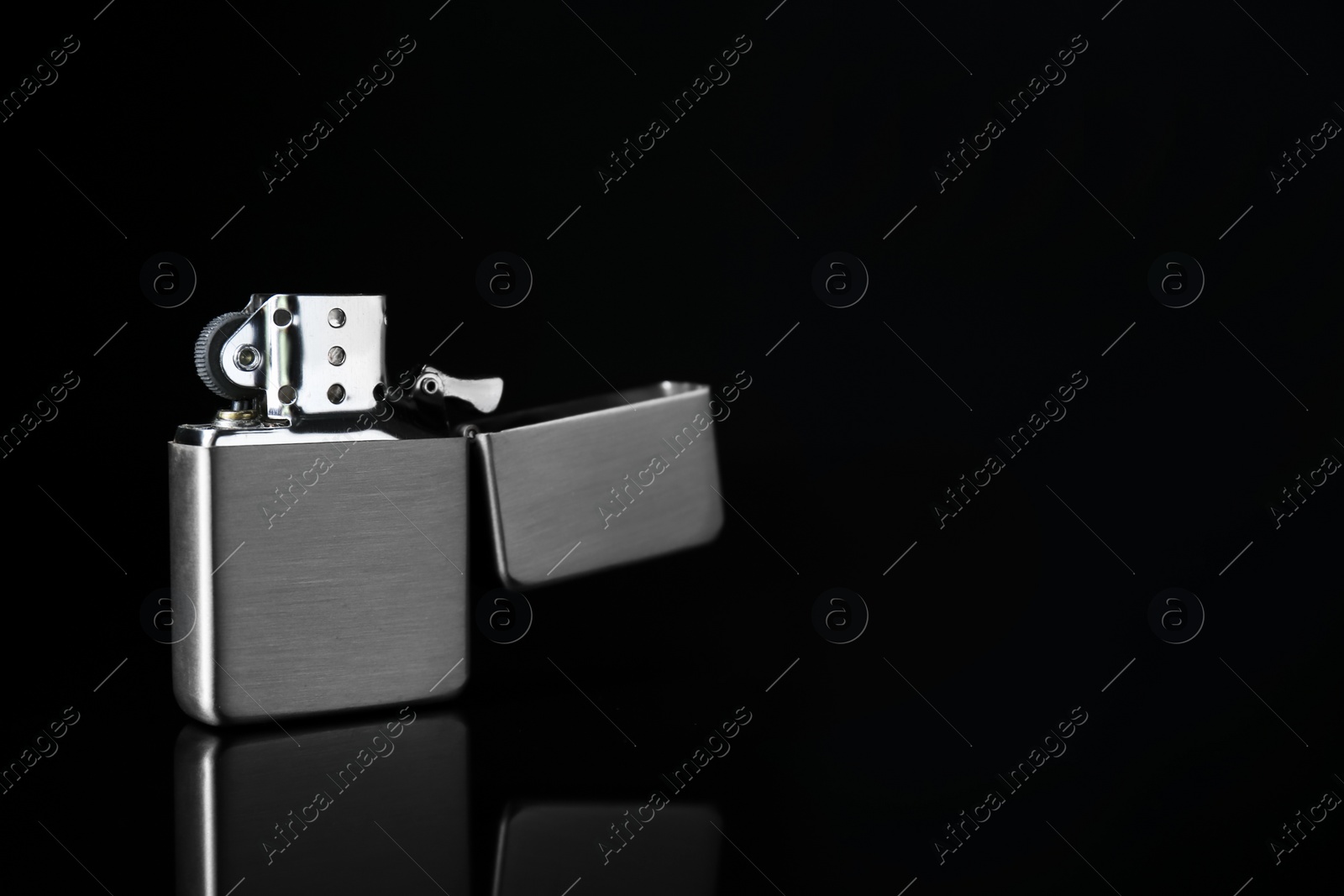 Photo of Gray metallic cigarette lighter on black background, space for text