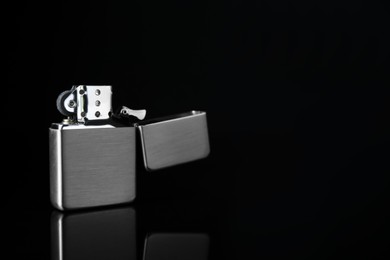 Gray metallic cigarette lighter on black background, space for text