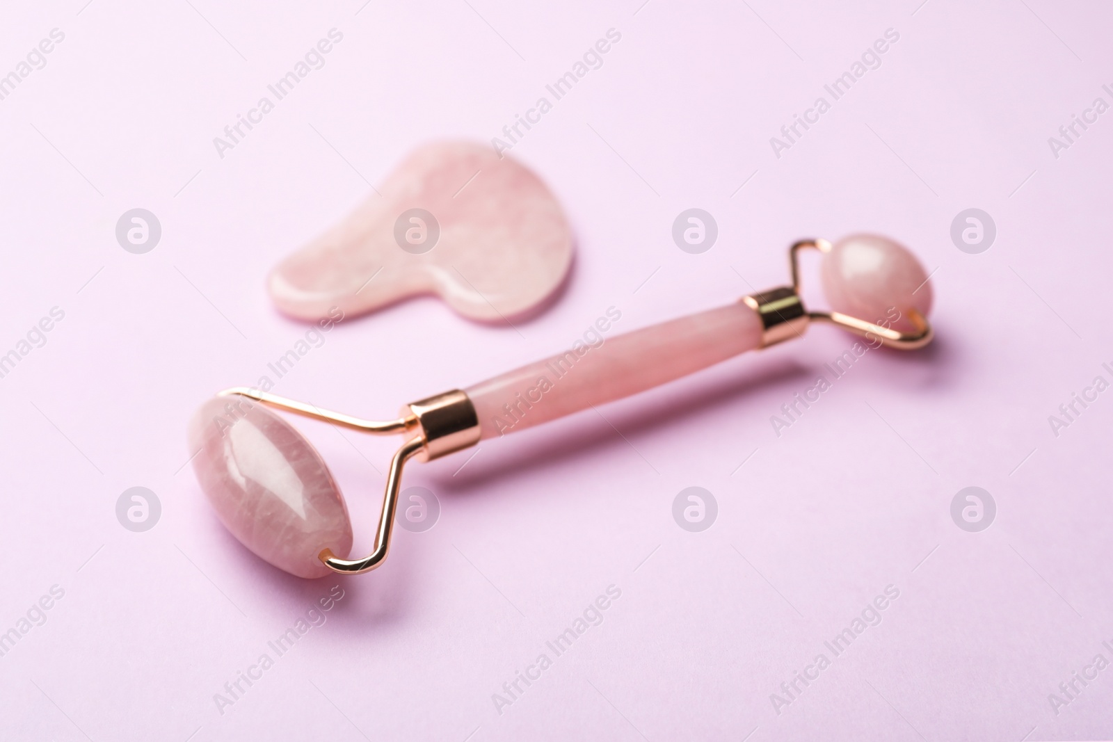 Photo of Natural face roller and gua sha tool on pink background