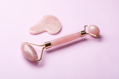 Natural face roller and gua sha tool on pink background